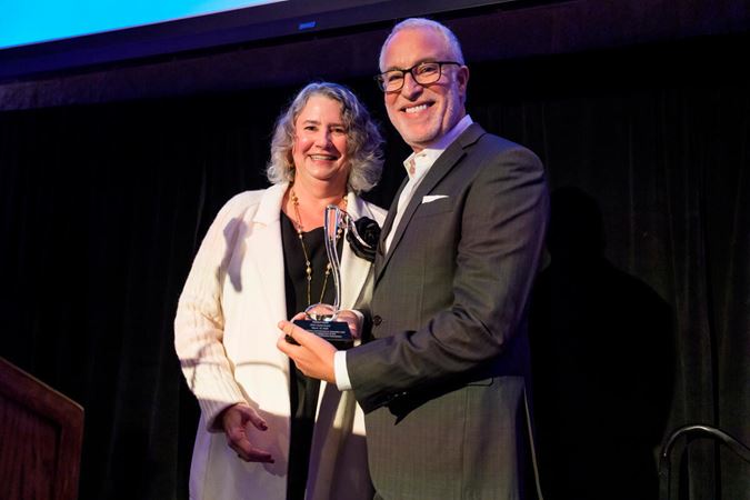 NMI Board Chair Leslie Burns presents IMPACT honoree Robert Kohl with the IMPACT Award.